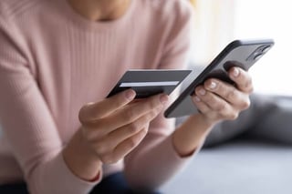 A woman uses a credit card to make a purchase using her smart phone.